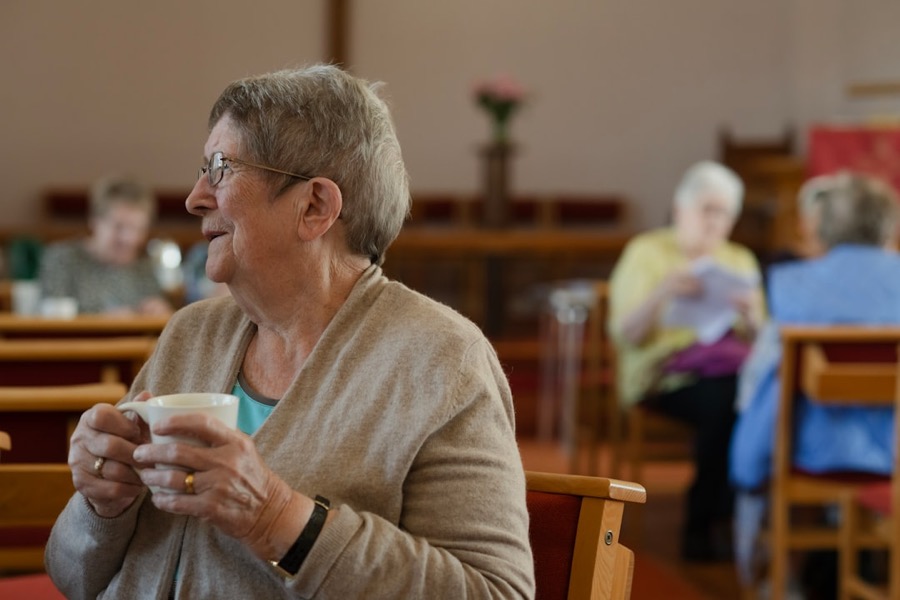 An older lady smiling over her morning tea